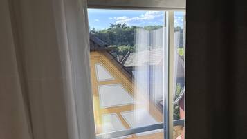 Una stanza con un'ampia finestra che si affaccia su un edificio tradizionale con tetto in tegole.