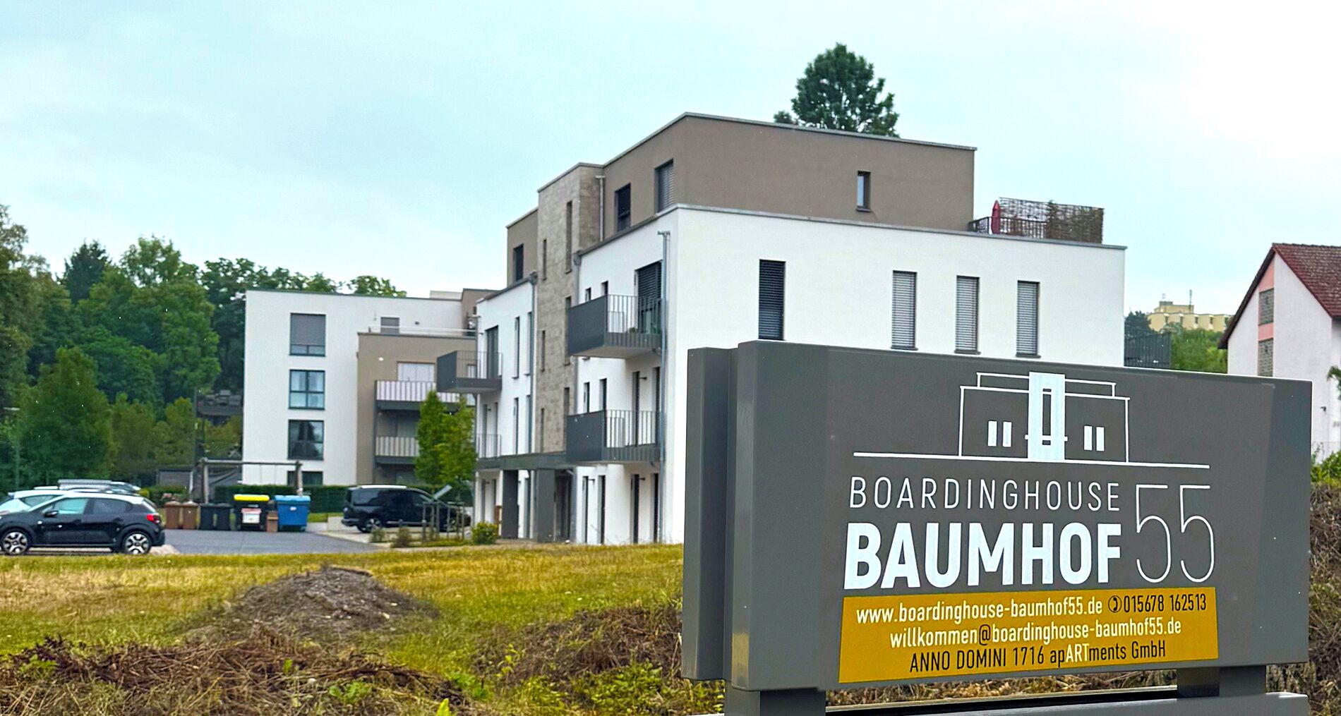 Ein modernes Gebäude mit einem Schild für 'Boardinghouse Baumhof 55', das ein Pensionhaus kennzeichnet.