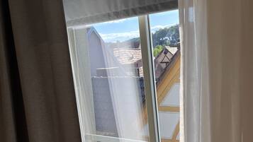 A window with a view of a building's roof and a clear sky.