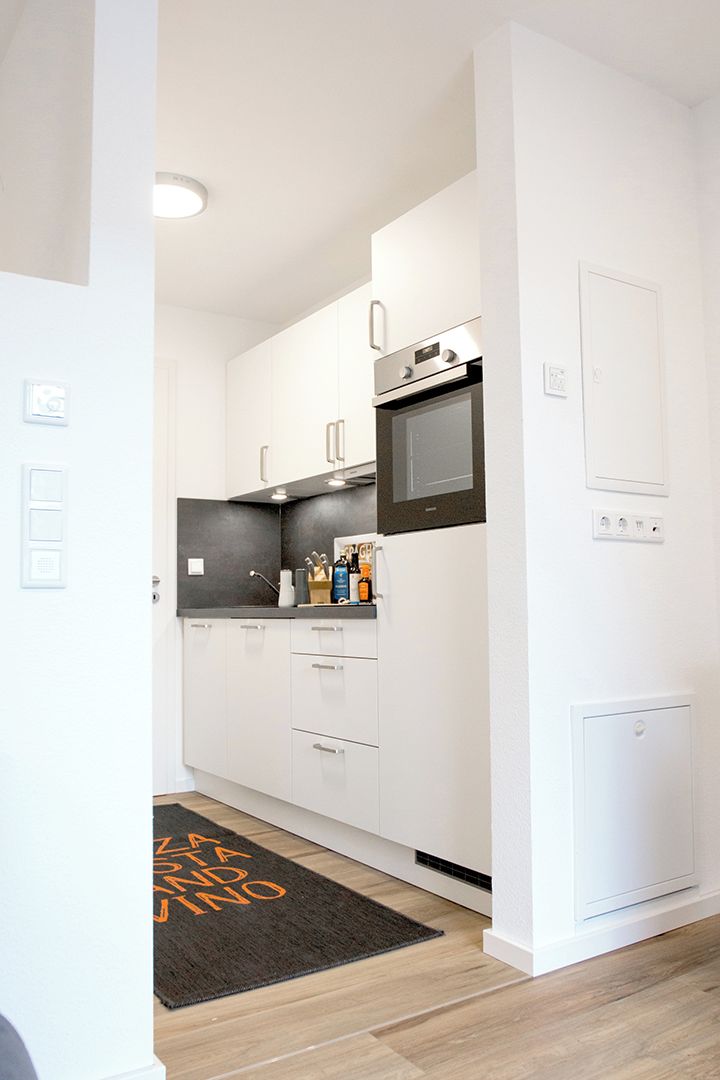 A modern kitchen with white cabinets, a black countertop, and a built-in oven.
