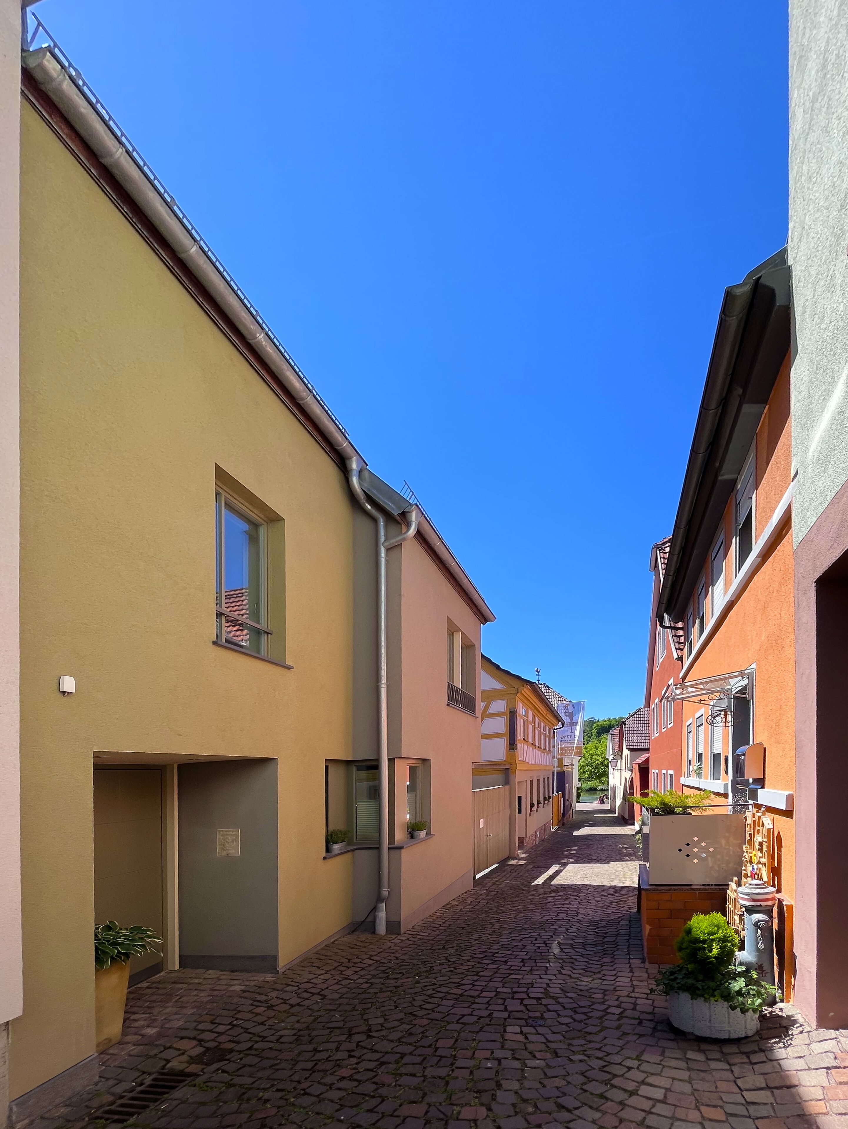A narrow cobblestone street lined with colorful buildings, featuring a mix of residential and commercial properties.