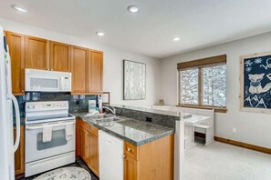 Una cocina con armarios de madera, un microondas blanco y una encimera de granito.