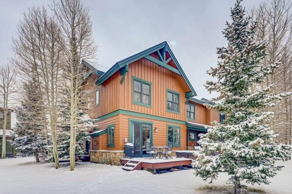 A two-story wooden house with a porch and a deck, surrounded by snow-covered trees. - Private Hot Tub, MountainScape Chalet! Paradise! (Breckenridge)