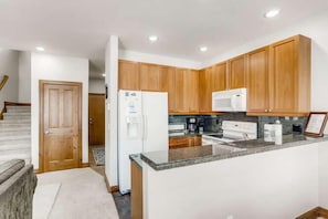 A modern kitchen with wooden cabinets, a granite countertop, a refrigerator, a microwave, and a coffee maker. - Family Hot Tub, MountainScape Chalet! Paradise! (Breckenridge)