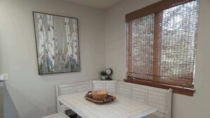 A corner room with a white bench, a table, and a window with a bamboo blind. - Family Hot Tub, MountainScape Chalet! Paradise! (Breckenridge)