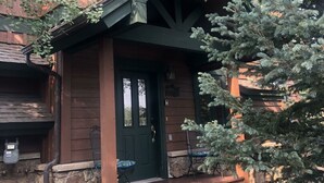 Un bâtiment en bois avec une porte verte et un petit porche.