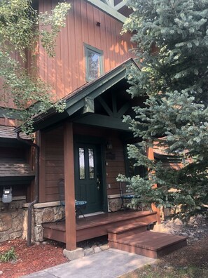 Un edificio de madera con una puerta verde y un pequeño porche.
