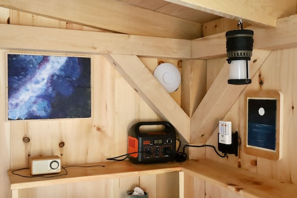 L’intérieur d’une cabane en bois, avec une radio, un télescope et une photographie encadrée du ciel nocturne.