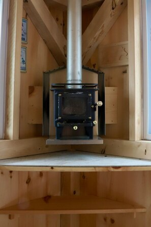 Un poêle à bois dans une cabane en bois, avec une cheminée en métal.