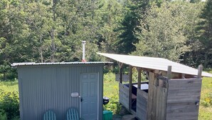 A small cabin with a door and two Adirondack chairs outside. - Tiny Cabin on Blue Hill Farm (Blue Hill)
