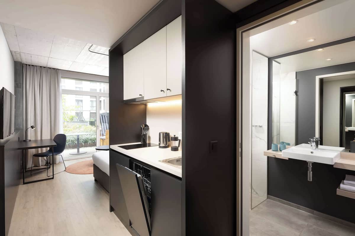 A modern kitchen with a dishwasher, a sink, and a countertop with a kettle and coffee maker.