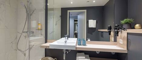 A modern bathroom with a glass-enclosed shower, a white sink, and a large mirror.