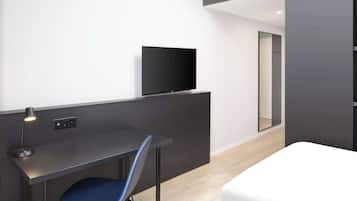 A modern hotel room with a desk, chair, and a flat-screen TV.