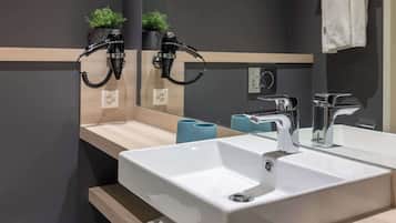 A modern bathroom with a large mirror, two sinks, and a towel rack.