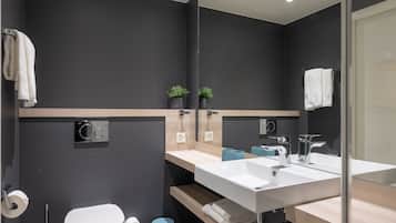 Un baño moderno con un espejo grande, un lavamanos blanco y un inodoro.