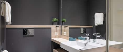 A modern bathroom with a large mirror, a white sink, and a toilet.