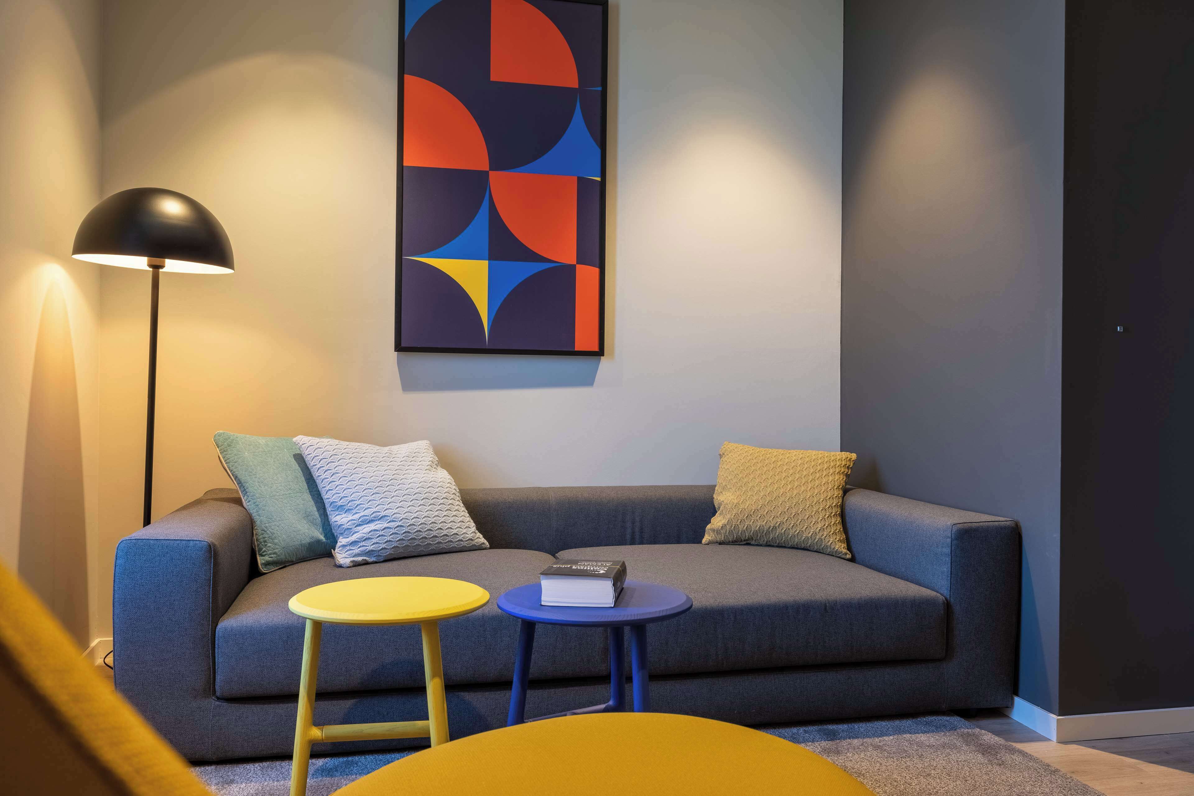 Ein modernes Wohnzimmer mit einem grauen Sofa, zwei kleinen runden Tischen und einer Stehlampe.