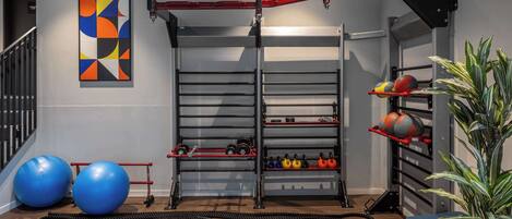 A home gym with exercise equipment, a pull-up bar, and a colorful abstract painting on the wall.