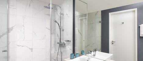 Une salle de bain moderne avec une douche à l’italienne, deux vasques blanches et un grand miroir.