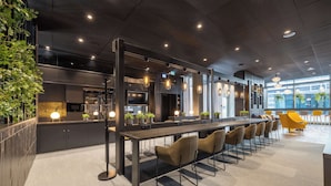 A modern conference room with a long table, chairs, and a TV. - Radisson Hotel & Suites Zurich (Opfikon)