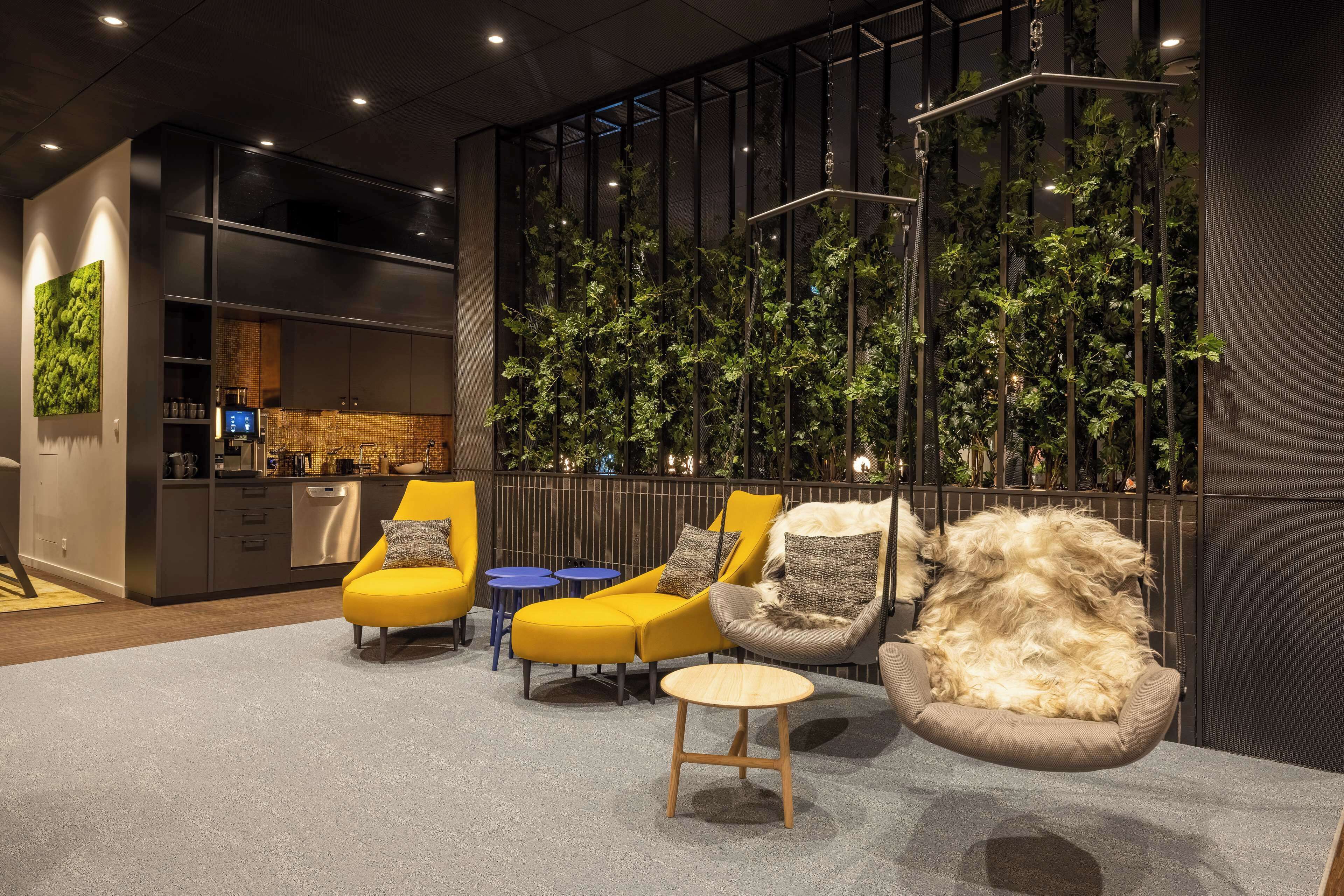Ein modernes Interieur mit Sitzbereichen, einer Küche und einer vertikalen Grünwand.