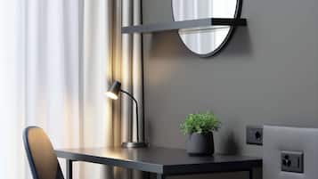 Un bureau moderne, agrémenté d’une lampe, d’une plante en pot et d’un miroir accroché au mur.