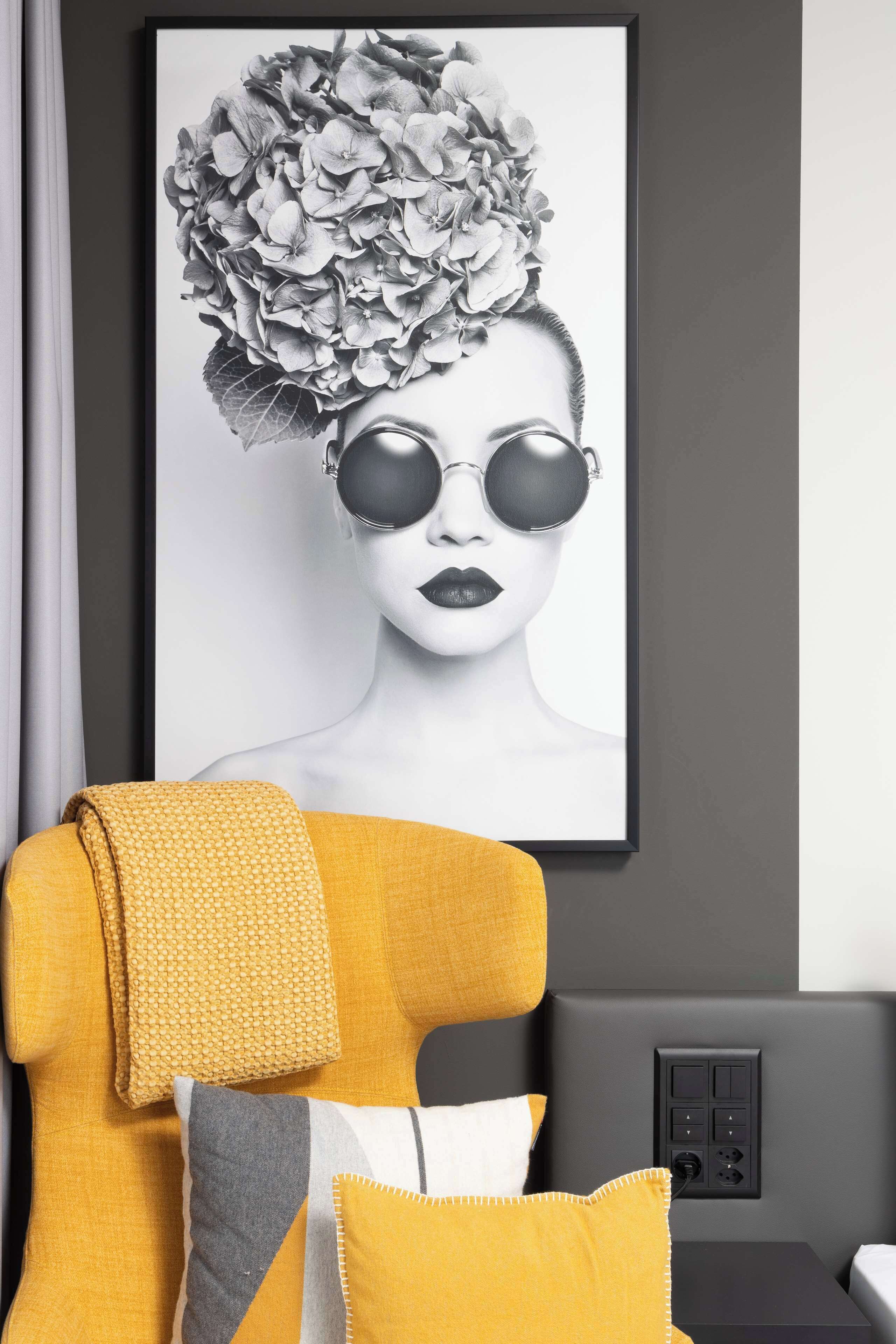 A modern room with a large framed artwork on the wall, a sofa with yellow cushions, and a side table with a power outlet.