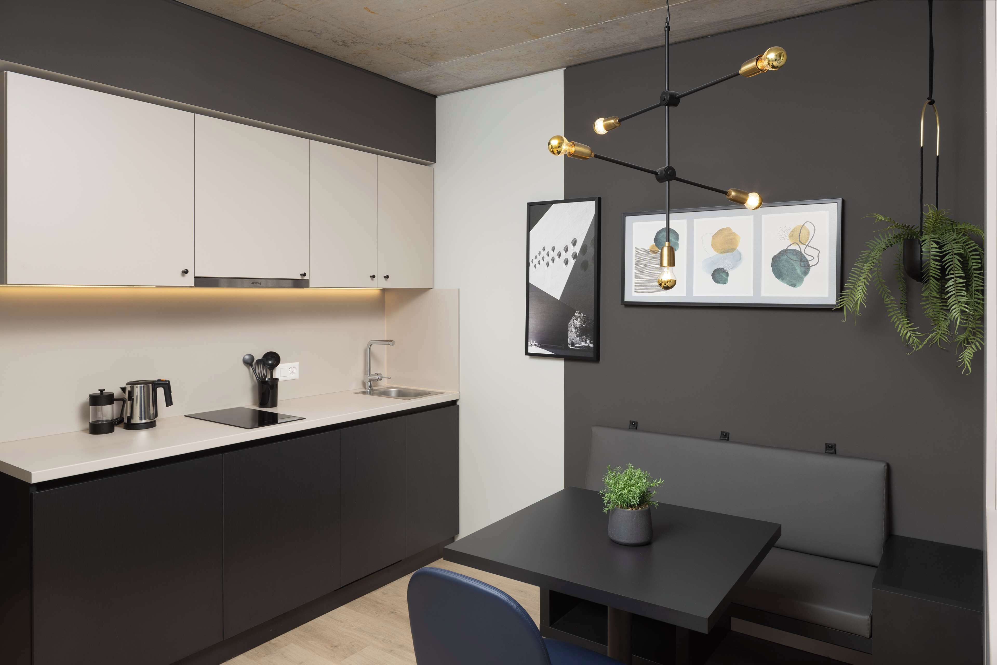 Una cocina moderna con estufa integrada, un lavamanos y una zona de comedor con banco y mesa.