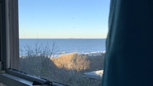 A window with a view of the sea and a distant shoreline. - Rustic Rooftop Delight - Bay Front 2 Bedroom Apts by RedAwning (Norfolk)