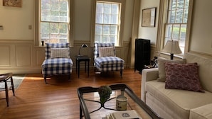 A living room with two plaid armchairs, a beige sofa, and a coffee table with books and a candle. - Rockport Home with Beautiful Ocean Views (Rockport)