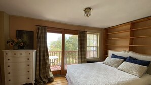 A bedroom with a large bed, a dresser, a window with curtains, and a balcony. - Rockport Home with Beautiful Ocean Views (Rockport)