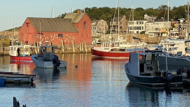 A harbor with boats docked, a red building, and houses in the background. - Rockport Home with Beautiful Ocean Views (Rockport)