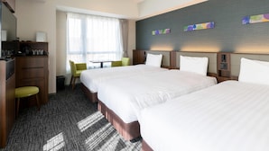 Habitación de hotel con dos camas, un escritorio, una silla y una ventana con cortinas.