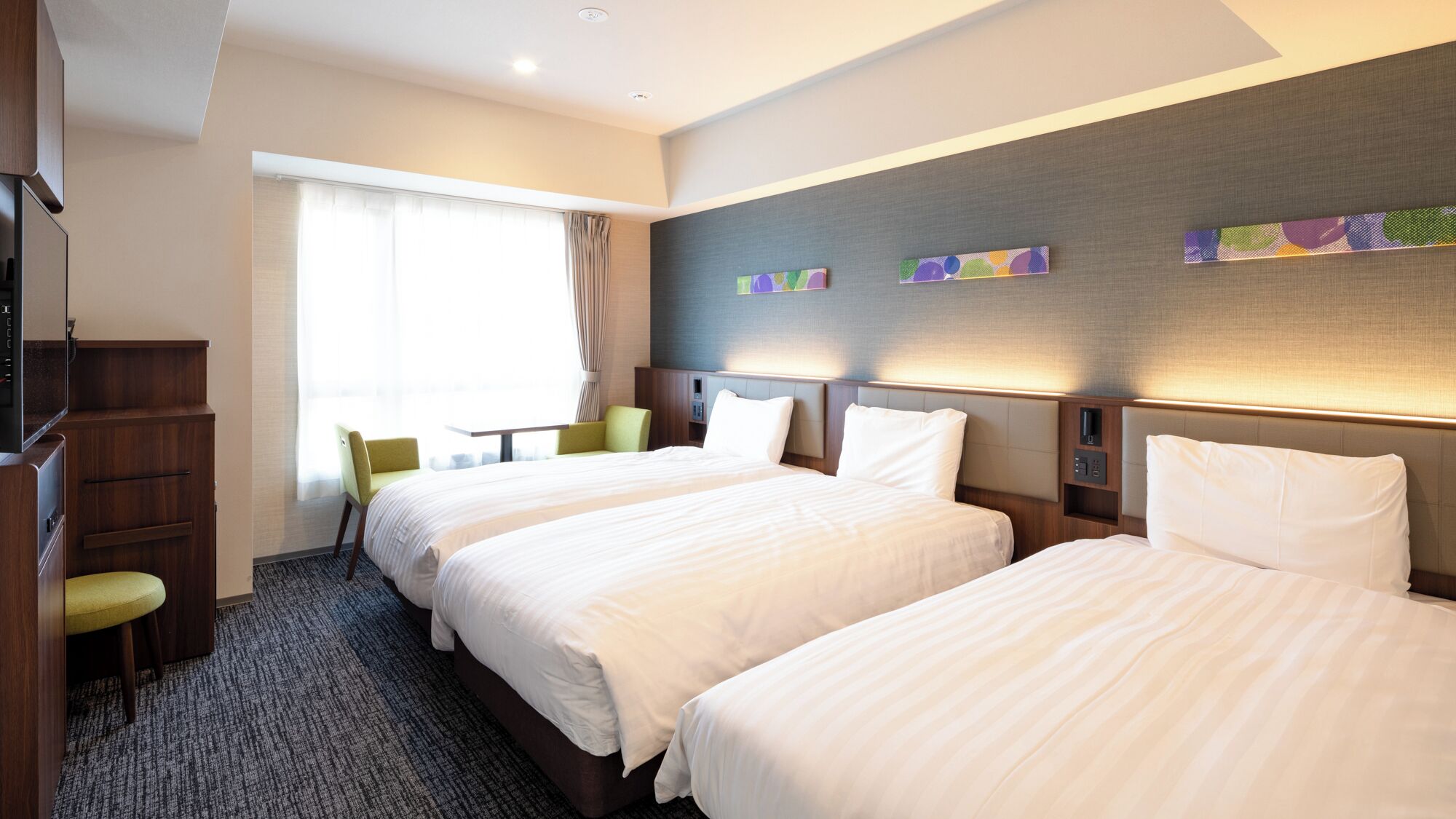 A hotel room with two beds, a desk, a chair, and a television.