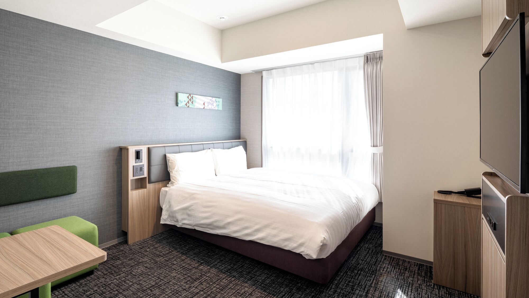 A hotel room with a bed, a desk, a television, and a window with curtains.