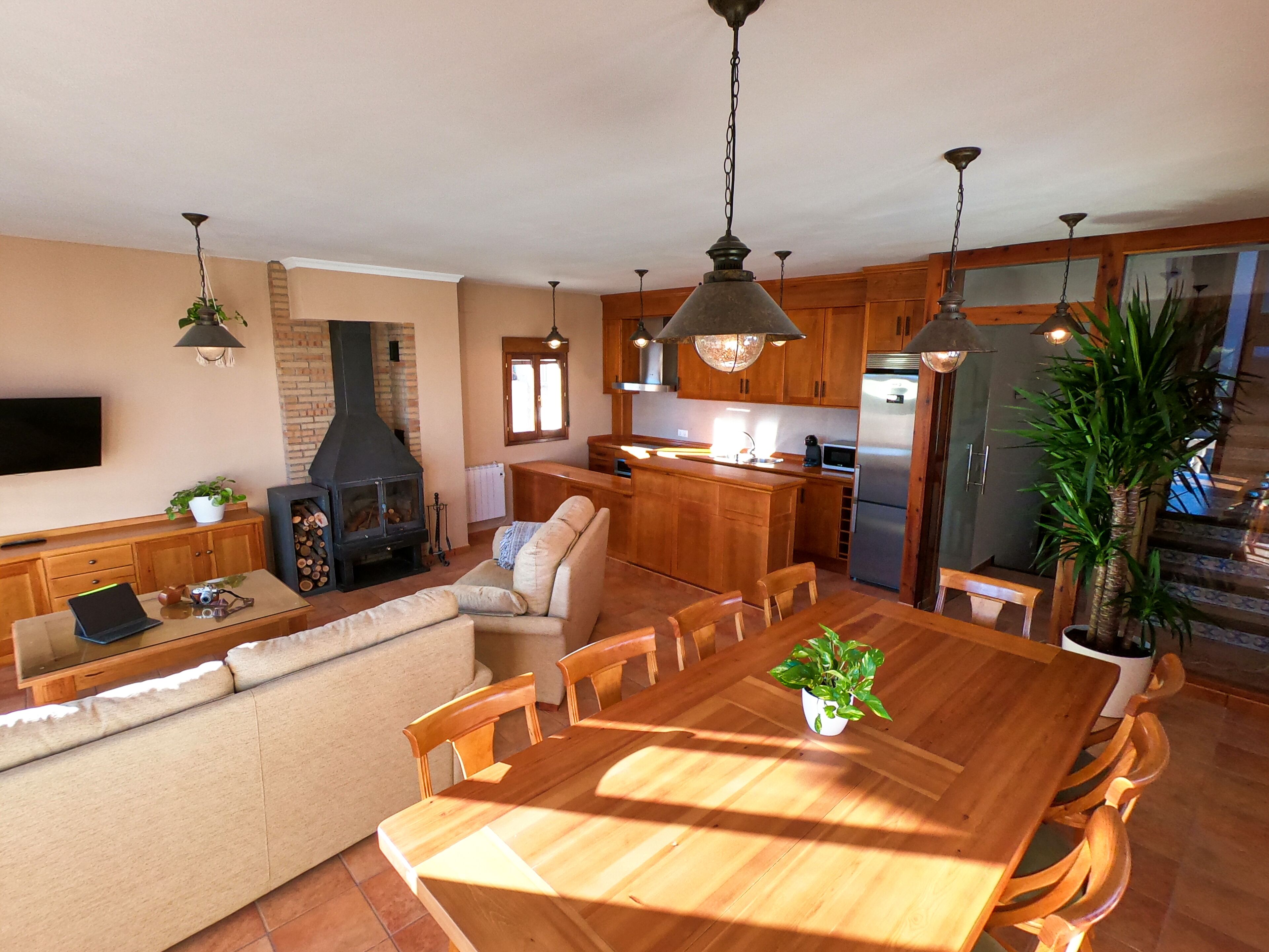 Un vaste espace de vie comprenant une table à manger en bois, un canapé et une cheminée.