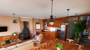 Uma sala de estar ampla com uma mesa de jantar de madeira, sofá e lareira.