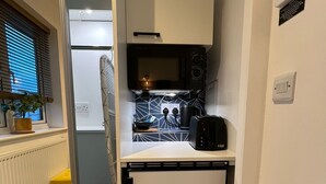 Una cocina compacta con microondas, un refrigerador pequeño y un lavamanos.