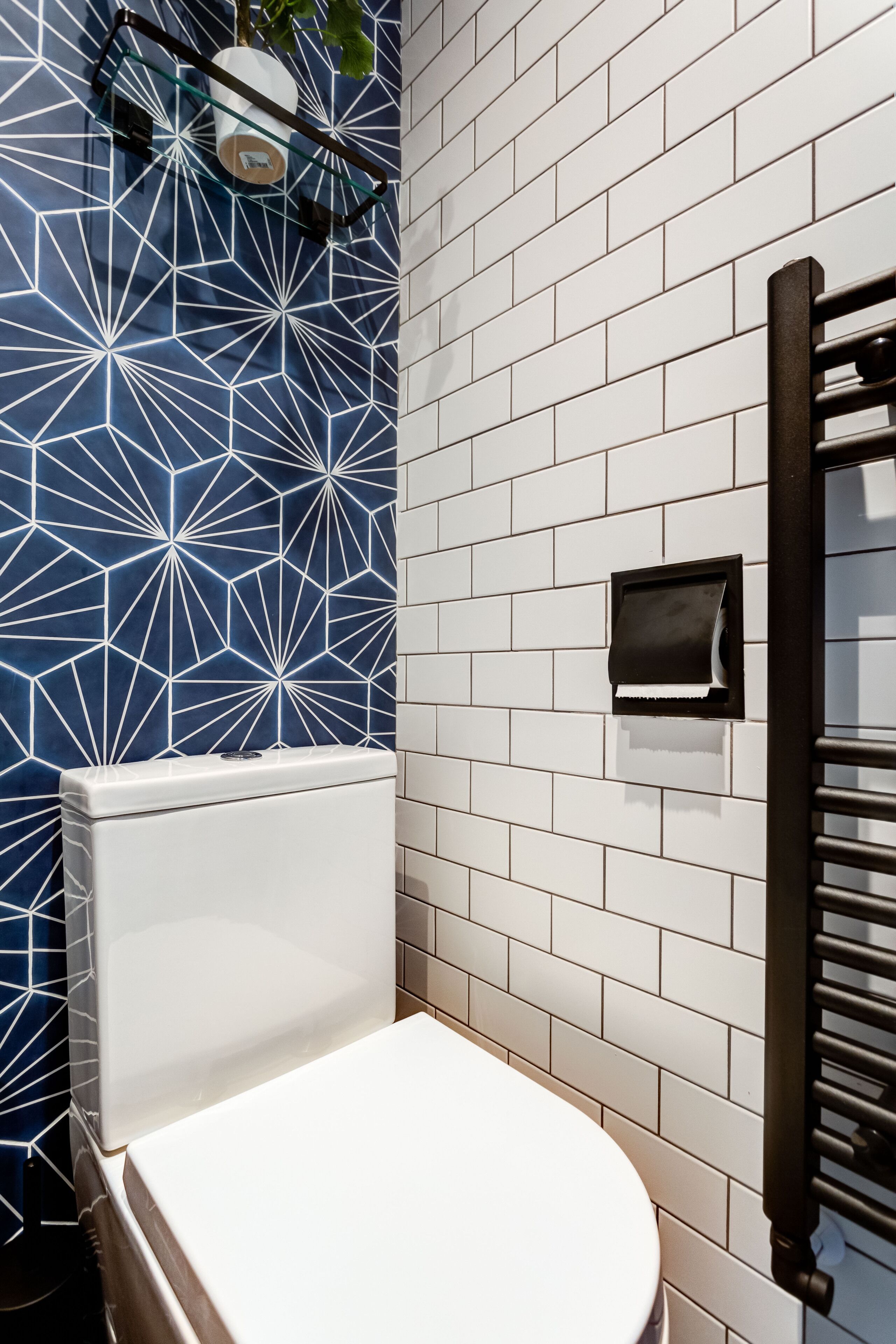 A bathroom with a white toilet, a towel rack, and a geometric-patterned wall.
