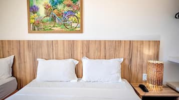 A hotel room with a wooden headboard, a bed with white bedding, a painting of a bicycle, and a bedside lamp.