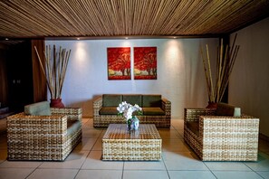 A room with wicker furniture, a central coffee table, and two paintings on the wall.