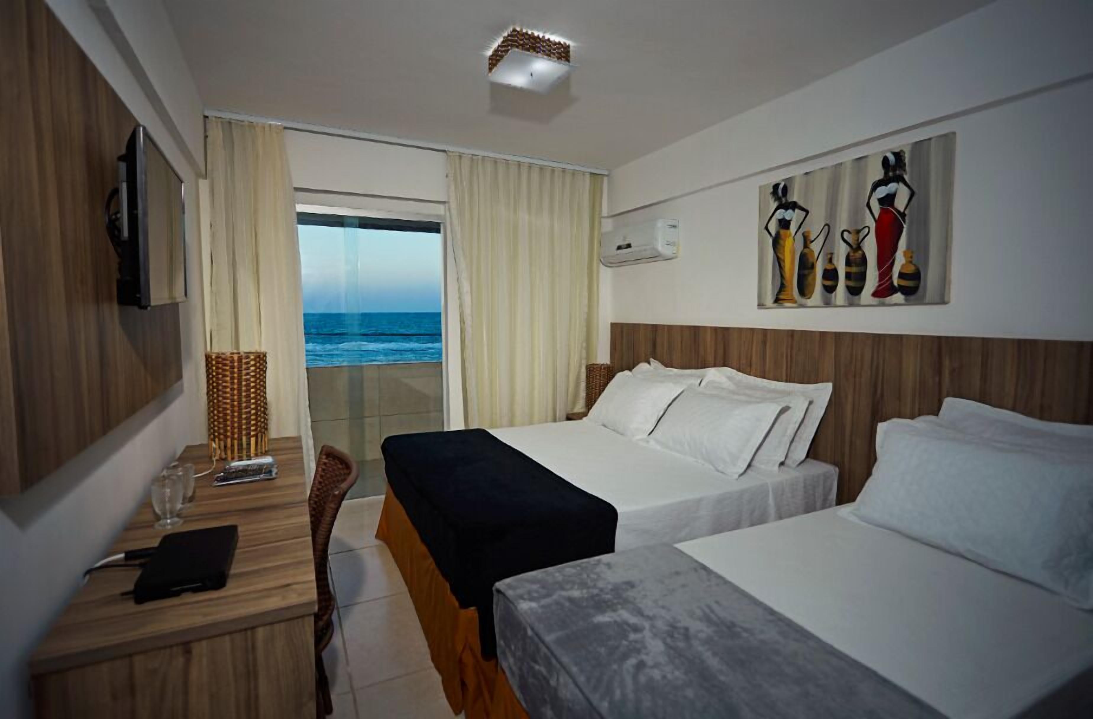 Habitación de hotel con dos camas, un escritorio con silla, televisión y un cuadro en la pared.