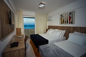 Habitación de hotel con dos camas, un escritorio con silla, televisión y un cuadro en la pared.