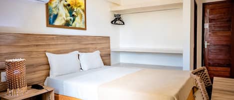 Una habitación de hotel con cama, mesita de noche, lámpara y una obra de arte.