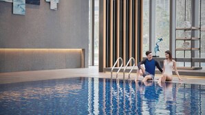 An indoor swimming pool with a modern design, including a wooden panel wall and a metal ladder.