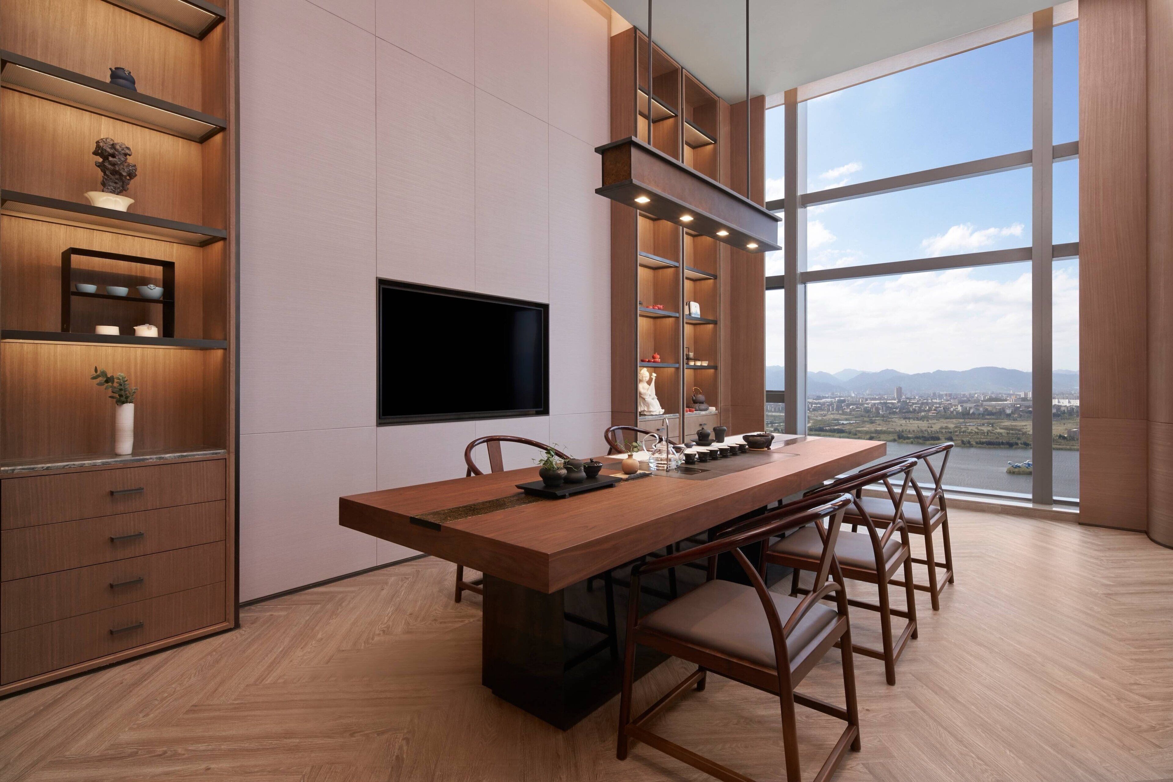 A modern dining area with a long wooden table, chairs, and built-in shelves.