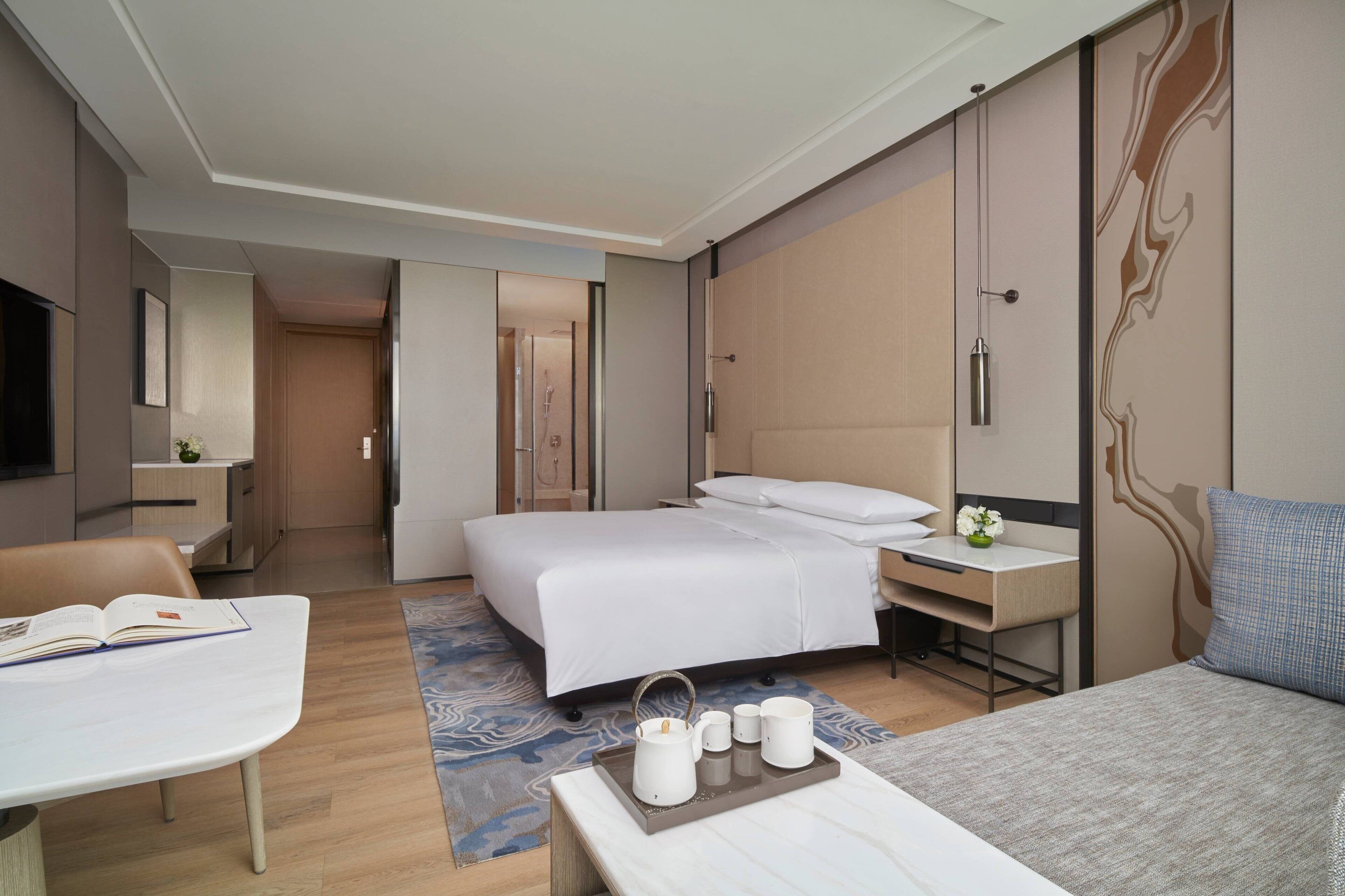 Een moderne hotelkamer met een bed, nachtkastje, bureau en televisie.