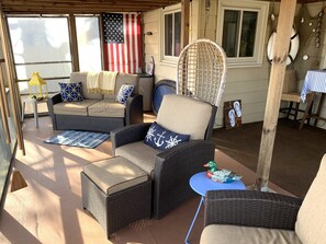 A covered patio area with wicker furniture, a blue table, and a decorative duck. - Quiet Lakefront Oasiswith hot tub and boat rental (Trevor)