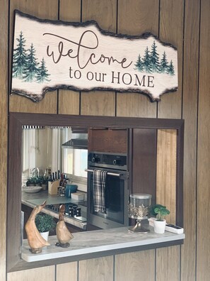 A kitchen with a wooden sign above the mirror that reads 'Welcome to our HOME.' - Quiet Lakefront Oasiswith hot tub and boat rental (Trevor)