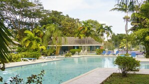 Ein Poolbereich mit Liegestühlen und einem Gebäude im Hintergrund.